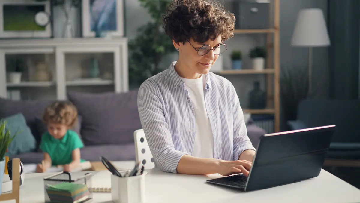 Elternteil im Homeoffice mit Kind im Hintergrund